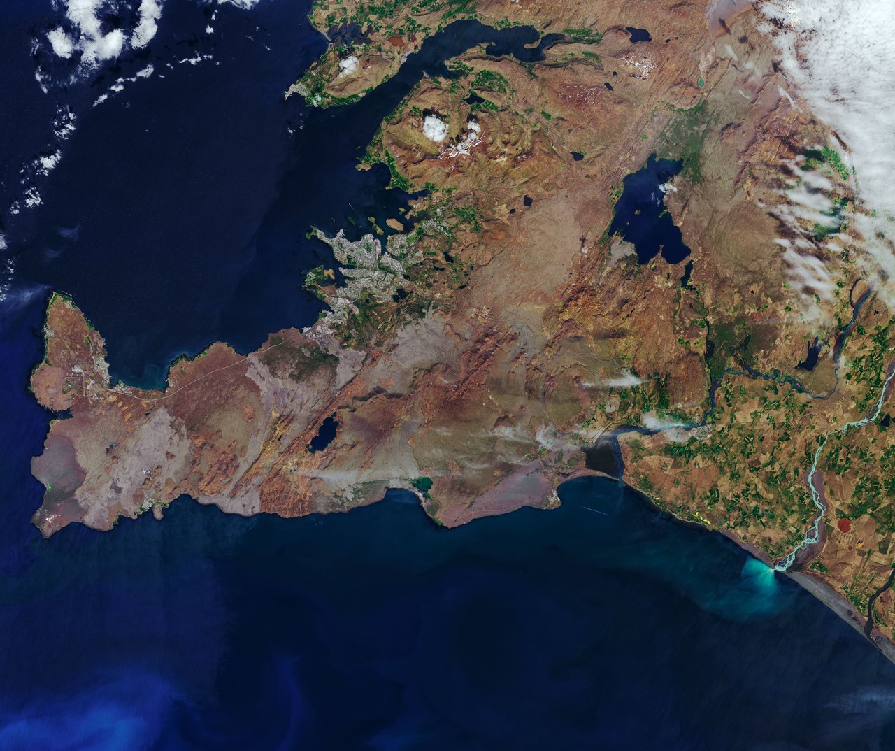 Landsat view of southwest Iceland, showing volcanic terrain, lakes, rivers, and pale sediment entering the Atlantic Ocean.