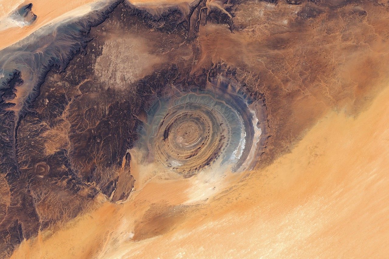 Landsat satellite view of the Eye of the Sahara: concentric ridges in a vast sand and charcoal desert landscape.